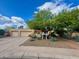 Beige single-story home with a three-car garage, xeriscaping, and mature desert trees at 9802 N 77Th St, Scottsdale, AZ 85258