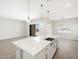 Bright kitchen features a white quartz island, stainless steel sink, and modern pendant lighting at 17561 W Pierson St, Goodyear, AZ 85395