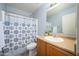 Bathroom with light blue accents featuring a shower with patterned curtain, toilet, vanity, and large mirror at 11501 W Charter Oak Rd, El Mirage, AZ 85335