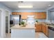 Bright kitchen features an island, stainless steel refrigerator, and wooden cabinetry for a functional and stylish space at 11501 W Charter Oak Rd, El Mirage, AZ 85335