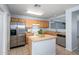 Bright kitchen features an island, stainless steel refrigerator, and wooden cabinetry for a functional and stylish space at 11501 W Charter Oak Rd, El Mirage, AZ 85335