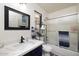 Well-lit bathroom with a single sink vanity, shower-tub with glass doors, dark blue accents, and storage at 4529 E Thistle Landing Dr, Phoenix, AZ 85044