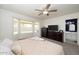 Comfortable main bedroom featuring large window with blinds, ceiling fan, dresser, and ensuite bathroom at 4529 E Thistle Landing Dr, Phoenix, AZ 85044