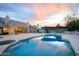Luxurious backyard with pool, outdoor kitchen, built-in seating, and manicured lawn under a vibrant sunset at 6718 E Caron Dr, Paradise Valley, AZ 85253