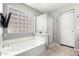 Bathroom featuring soaking tub with tile surround, glass block window, and glass-door shower at 9259 W Caron Cir, Peoria, AZ 85345