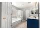 Bright bathroom featuring a soaking tub, step-in shower with glass door, and a blue double vanity at 9259 W Caron Cir, Peoria, AZ 85345