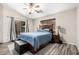 Cozy bedroom with wood-look flooring, ceiling fan, stylish bed frame and headboard, and sliding glass doors at 9259 W Caron Cir, Peoria, AZ 85345