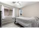 This bedroom features a ceiling fan, light gray walls and matching gray floors, a window and bright white curtains at 9259 W Caron Cir, Peoria, AZ 85345