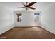 Bright bedroom featuring two windows, brown carpet, and a ceiling fan at 12217 W Planada Ln, Sun City, AZ 85373