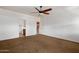 Spacious bedroom showcasing a ceiling fan, neutral carpet, and doorways leading to a bathroom and other rooms at 12217 W Planada Ln, Sun City, AZ 85373