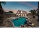 Backyard pool with rock features, palm trees, solar panels, and patio with a covered pergola at 12745 W Monte Vista Rd, Avondale, AZ 85392