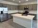Well-lit kitchen featuring gray cabinets, stainless steel appliances, large island, and subway tile backsplash at 25342 W Bowker St, Buckeye, AZ 85326