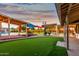 Expansive backyard featuring a putting green, pool with waterfall, covered patios, and outdoor entertainment spaces at 368 E Campbell Rd, Chandler, AZ 85225