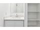 Bright bathroom featuring a white vanity with a modern sink and mirror, complemented by open storage shelves at 12246 E Agave Ln, Florence, AZ 85132