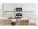 Modern kitchen featuring stainless steel appliances, white countertops and cabinets, and stylish bar stools at 12246 E Agave Ln, Florence, AZ 85132