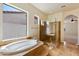 Spa-like bathroom featuring a soaking tub, glass-enclosed shower, and tile flooring at 14112 N 12Th St, Phoenix, AZ 85022