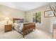 Cozy bedroom with a wood frame bed, carpeted floors, and a view to a tree lined backyard at 19005 N Diamante Dr, Surprise, AZ 85387