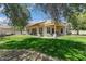 Lush backyard featuring covered patio, mature trees, and green grass at 20627 W Grandview Dr, Buckeye, AZ 85396