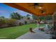 Covered patio with ceiling fans overlooks a grassy backyard with mature landscaping and perimeter walls at 20627 W Grandview Dr, Buckeye, AZ 85396