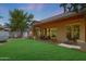 Expansive backyard featuring a lush lawn, covered patio, and mature trees at 20627 W Grandview Dr, Buckeye, AZ 85396