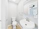 Clean bathroom with a pedestal sink, modern toilet, and a wall-mounted mirror at 2628 W Marshall Ave, Phoenix, AZ 85017
