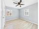 Bright bedroom featuring wood-look floors, modern ceiling fan, and natural light from two windows at 2628 W Marshall Ave, Phoenix, AZ 85017