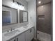 Bathroom featuring double sinks, framed mirrors, white cabinets, and a tiled walk-in shower at 26308 W Camino Del Sol --, Casa Grande, AZ 85193