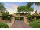 Stately home entrance with iron gates, brick driveway, and lush, mature landscaping at 27050 N 103Rd St, Scottsdale, AZ 85262