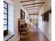 A neutral hallway with herringbone tile flooring and beam ceilings, with a rustic bench and interesting artwork at 27050 N 103Rd St, Scottsdale, AZ 85262