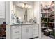 Bright bathroom with white cabinetry, a large mirror, and organized shelving for storage at 30857 N 128Th Dr, Peoria, AZ 85383