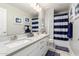 Bright bathroom with a double vanity, stylish mirrors, and a shower-tub combination with a striped curtain at 30857 N 128Th Dr, Peoria, AZ 85383