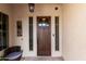 Inviting front porch with a dark wooden front door, decorative wreath, and seating area at 30857 N 128Th Dr, Peoria, AZ 85383