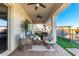 Inviting covered patio with wicker furniture, ceiling fans, and views of the beautifully landscaped backyard and pool at 30857 N 128Th Dr, Peoria, AZ 85383