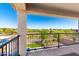 Covered patio with wrought iron railing offering panoramic views of the lush backyard and surrounding landscape at 30857 N 128Th Dr, Peoria, AZ 85383