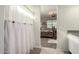 Bathroom with a glimpse into a bedroom, featuring a striped shower curtain and neutral color scheme at 36204 W San Sisto Ave, Maricopa, AZ 85138