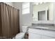 A functional bathroom featuring a granite countertop, toilet, and plaid shower curtain at 36204 W San Sisto Ave, Maricopa, AZ 85138