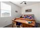 A cozy bedroom featuring a ceiling fan, wooden desk, and patriotic decor at 36204 W San Sisto Ave, Maricopa, AZ 85138