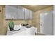 Functional laundry room with modern washer and dryer, plus storage shelving and cabinets at 4034 E Aster Dr, Phoenix, AZ 85032