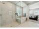 Bright bathroom featuring a free-standing tub, a glass enclosed shower, marble floors and plantation shutters at 4619 N 179Th Dr, Goodyear, AZ 85395
