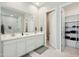 Bright bathroom featuring double sinks, marble floors, and an adjacent open closet with shelving at 4619 N 179Th Dr, Goodyear, AZ 85395