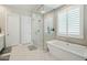 Bright bathroom featuring a free-standing tub, a glass enclosed shower and natural light from plantation shutters at 4619 N 179Th Dr, Goodyear, AZ 85395