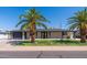 Charming single-story home featuring mature palm trees, freshly cut grass, and a dark gray attached garage at 5452 E University Dr, Mesa, AZ 85205