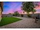 Serene backyard featuring artificial turf, desert landscaping and a backdrop of trees beneath a vibrant sunset sky at 5752 N 109Th Ave, Phoenix, AZ 85037