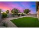 Beautiful backyard featuring lush turf and desert landscaping complemented by a stunning sunset backdrop at 5752 N 109Th Ave, Phoenix, AZ 85037