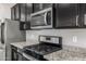 Modern kitchen features stainless steel appliances and granite countertops with stylish black cabinetry at 5752 N 109Th Ave, Phoenix, AZ 85037