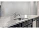 Close-up on a kitchen island featuring a granite countertop and stainless steel sink with faucet at 5752 N 109Th Ave, Phoenix, AZ 85037