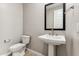 Clean powder room with pedestal sink, dark framed mirror, and tiled floors at 5856 E Covey Ln, Phoenix, AZ 85054