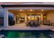 Covered patio with an outdoor kitchen, dining area, and ample seating, ideal for hosting gatherings and enjoying the pool at 644 E Las Puertas Ln, Queen Creek, AZ 85140