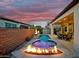 Backyard oasis with sparkling pool, spa, fire features, and covered patio at sunset at 644 E Las Puertas Ln, Queen Creek, AZ 85140