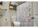 Bright bathroom with toilet, floral curtain, and wooden storage shelves at 6728 N 24Th Dr, Phoenix, AZ 85015